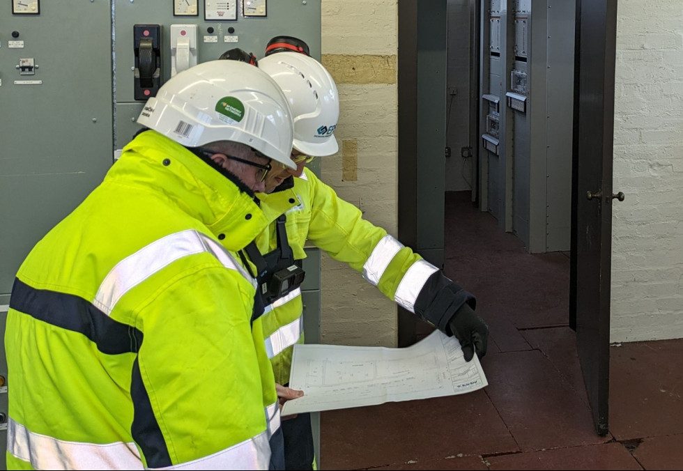 Two experienced electrical engineers studying a single line diagram during a site survey