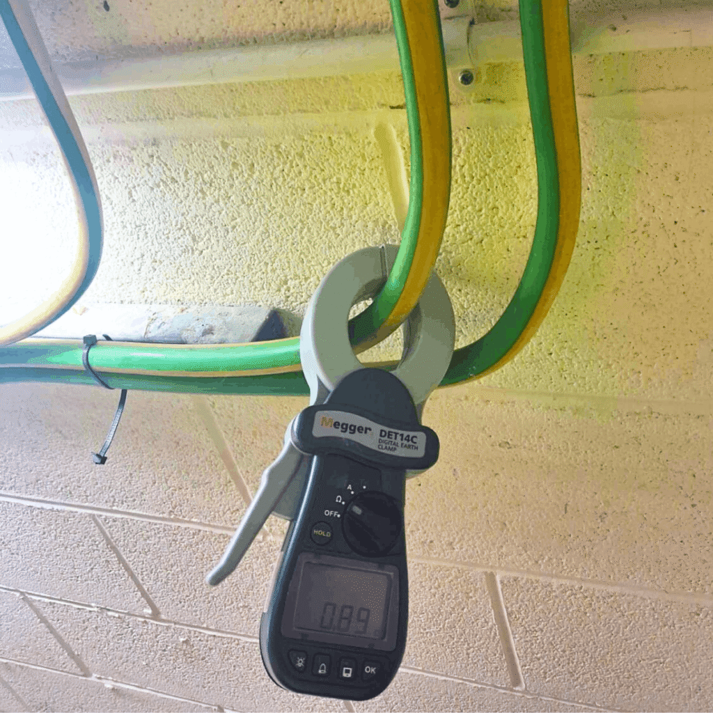 Clamp meter testing of earthing conductors during an HV earthing inspection at an industrial facility