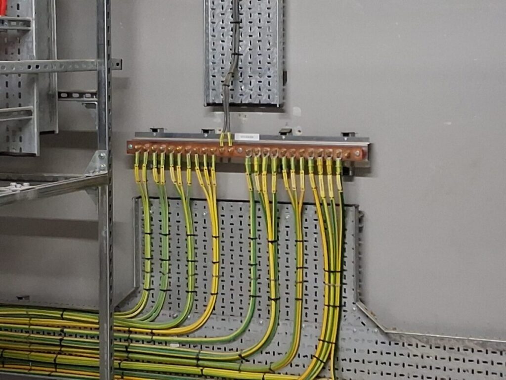 Copper earthing busbar with multiple green and yellow earth conductors.